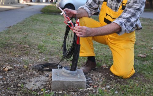 Worker installing optic fiber cables for internet and telephone, power lines installation at street